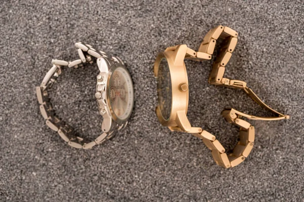 Top view of wristwatches lying on sand — Stock Photo