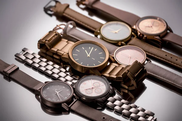 Montres-bracelets de luxe avec aiguilles d'horloge sur fond gris — Photo de stock