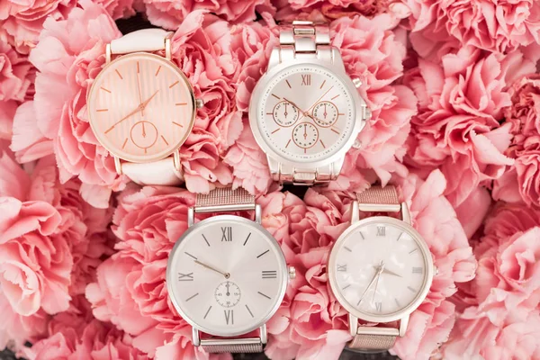 Von oben auf Armbanduhren, die auf blühenden rosa Blumen liegen — Stockfoto