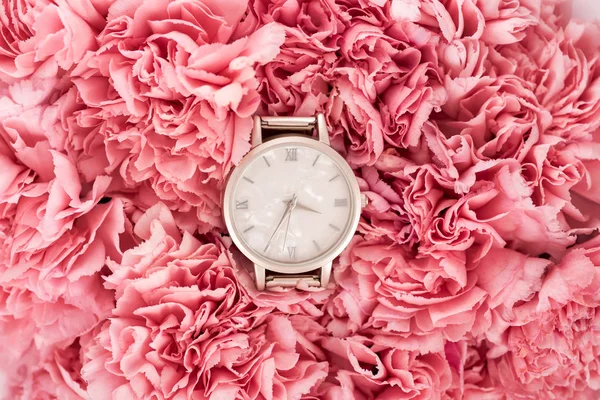 Vista superior del lujoso reloj de pulsera suizo acostado sobre flores en flor - foto de stock