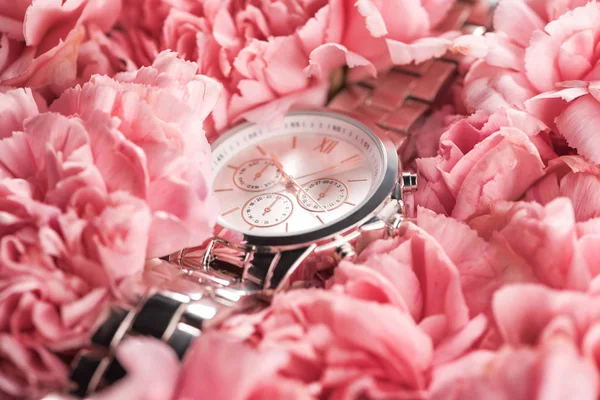 Elegant wristwatch lying on blooming pink flowers — Stock Photo