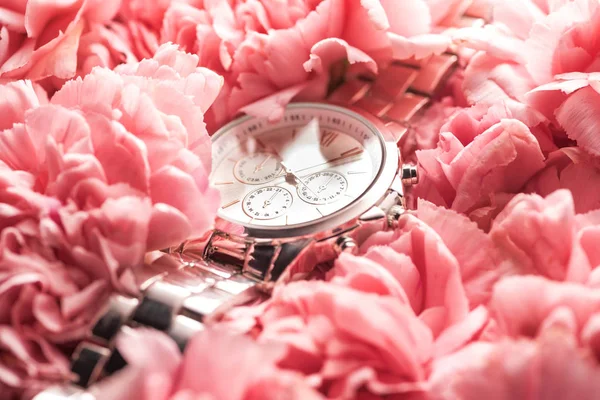 Swiss wristwatch lying on blooming pink flowers — Stock Photo