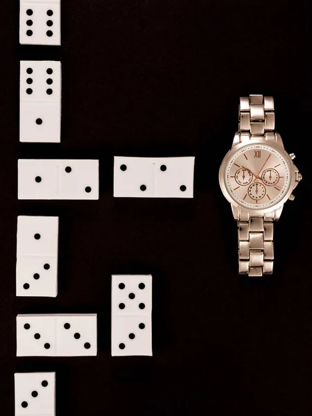 Top view of luxury wristwatch lying near dominoes isolated on black — Stock Photo