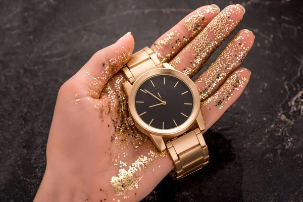 Cropped view of golden wristwatch in hand of woman — Stock Photo
