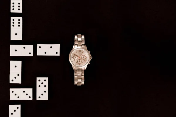 Top view of luxury wristwatch lying near dominoes isolated on black — Stock Photo