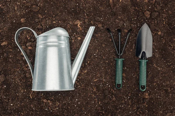 Top view of watering can near gardening tools on ground, protecting nature concept — Stock Photo