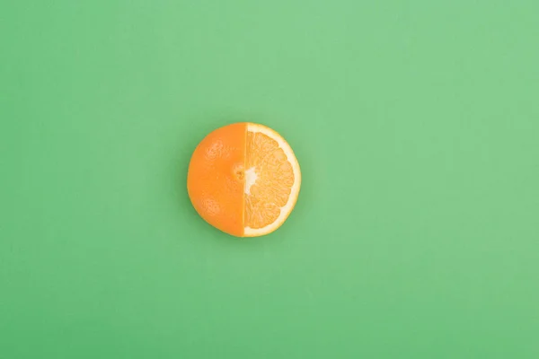 Vista superior de la fresca madura jugosa parcialmente cortada naranja sobre fondo verde - foto de stock