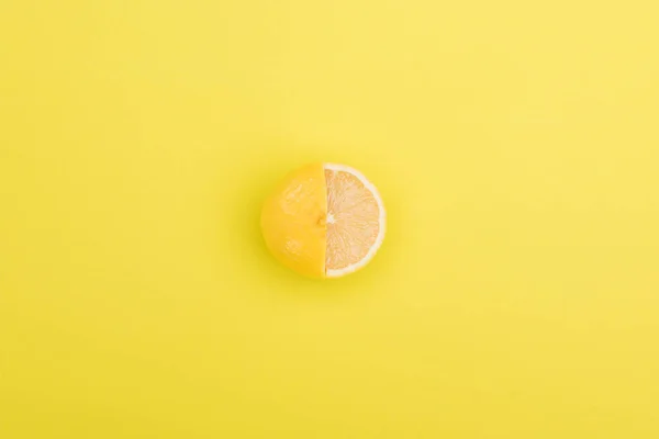 Vista superior de limón fresco y jugoso parcialmente cortado sobre fondo naranja - foto de stock