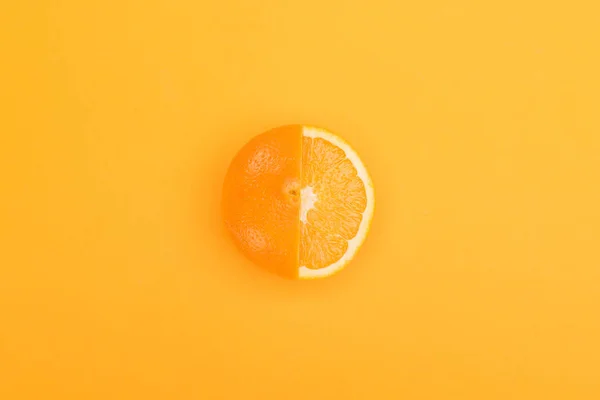 Vista superior de la naranja fresca madura parcialmente cortada sobre fondo naranja - foto de stock