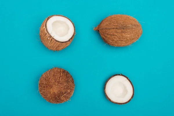 Ansicht von ganzen Kokosnüssen und Kokosnusshälften auf blauem Hintergrund — Stockfoto