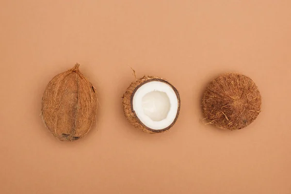 Top view of whole coconut and coconut halves on brown background — Stock Photo