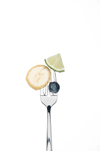 Arándanos enteros, rodajas de lima y plátano en un tenedor aislado en blanco - foto de stock