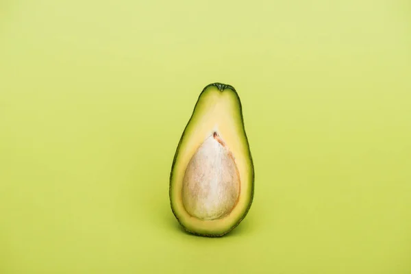 Die Hälfte der reifen frischen, schmackhaften Avocado auf grünem Hintergrund — Stockfoto