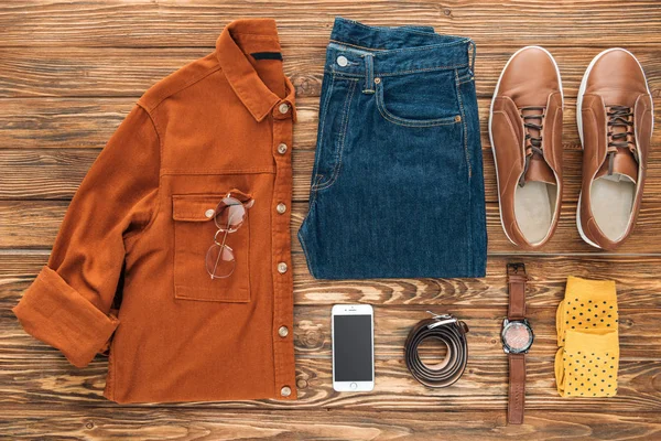 Flat lay with smartphone and male clothes on wooden background — Stock Photo