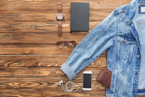 Posa piatta con giacca in denim, smartphone e accessori su sfondo in legno — Foto stock