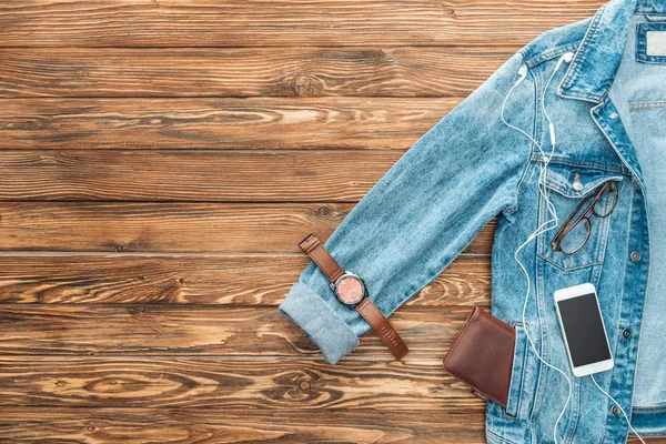 Vue du dessus de la veste en denim, montre-bracelet et smartphone sur fond en bois — Photo de stock