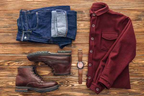 Flache Lage mit Hemd, Jeans und braunen Stiefeln auf hölzernem Hintergrund — Stockfoto