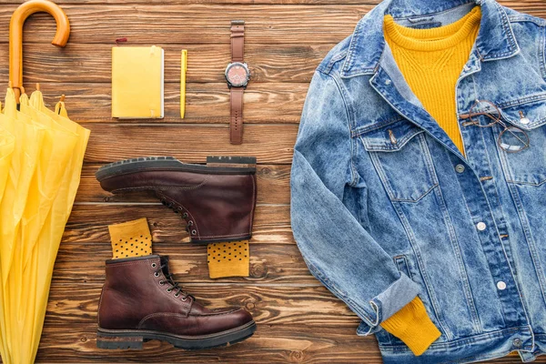 Плоский лежак з джинсовою курткою, жовта парасолька та підручник на дерев'яному фоні — стокове фото