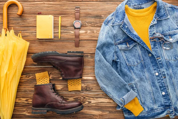 Pose plate avec veste en denim, parapluie jaune et manuel sur fond en bois — Photo de stock