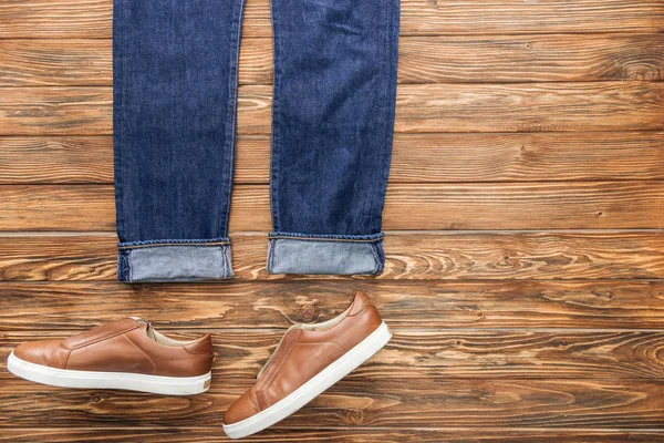Vista superior de jeans azules y zapatos sobre fondo de madera - foto de stock