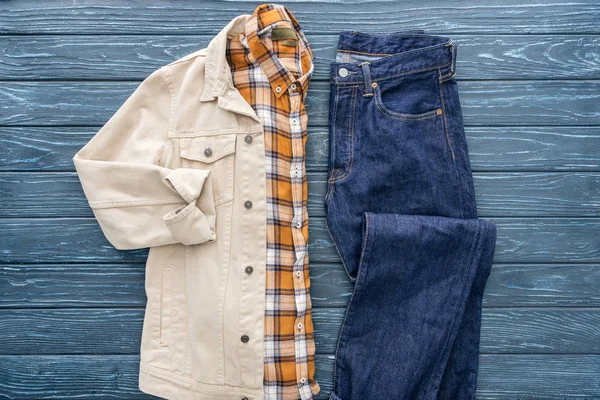 Vista superior de camisa a cuadros, chaqueta y jeans sobre fondo de madera - foto de stock