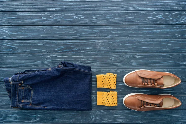 Top view of jeans, yellow socks and boots on wooden background — Stock Photo