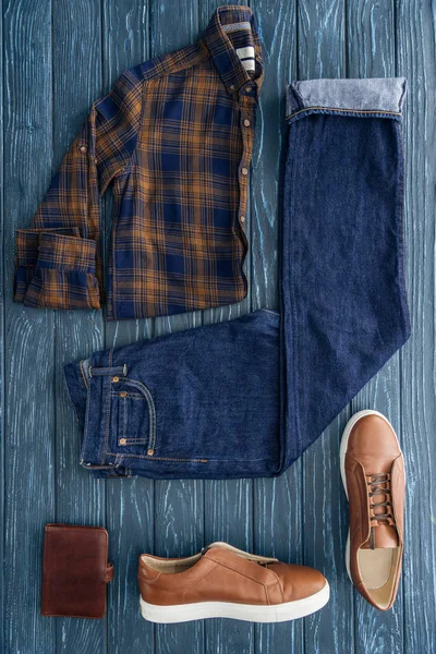 Pose plate avec chemise à carreaux, jeans et bottes sur fond en bois — Photo de stock