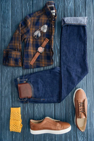 Flat lay com camisa quadriculada na moda, jeans e botas marrons em fundo de madeira — Fotografia de Stock