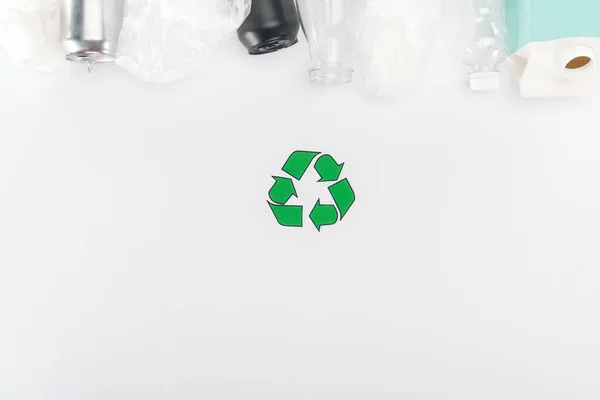 Draufsicht auf Dosen, Plastiktüten, Kartonflaschen, Glas- und Plastikflaschen auf weißem Hintergrund mit Recyclingschild — Stockfoto