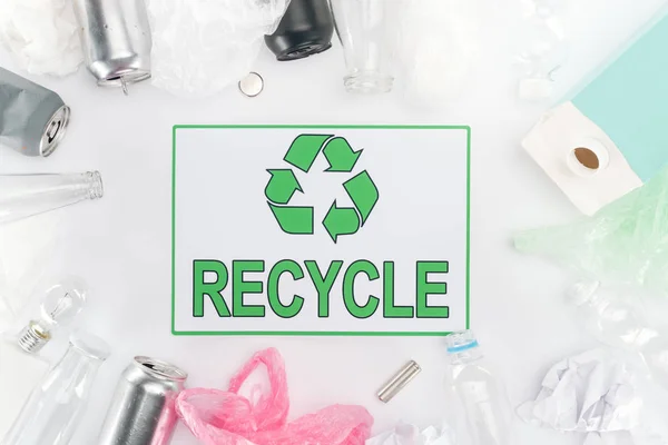 Cans, plastic and glass bottles, batteries, paper, bulb, carton bottle and plastic bags with recycling sign — Stock Photo