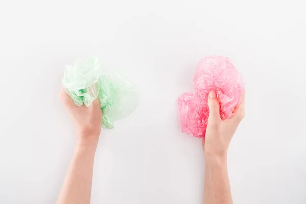 Cropped view of woman holding pink and green plastic bags on grey background — Stock Photo