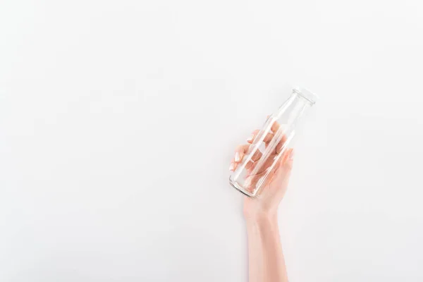 Cropped view of woman holding empty glass bottle on grey background — Stock Photo