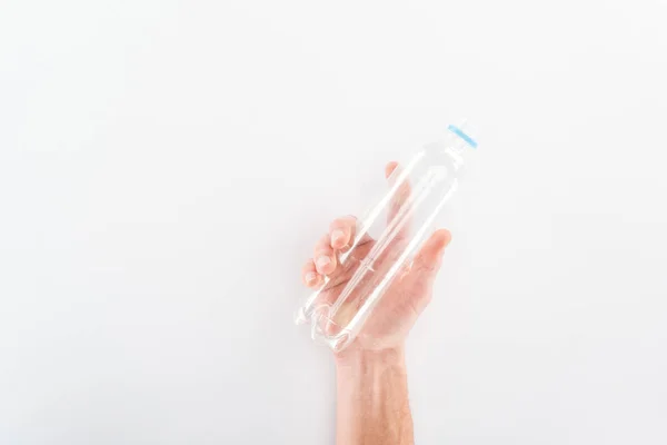 Обрізаний вид людини, що тримає порожню пластикову пляшку на сірому фоні — стокове фото