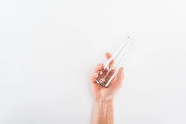 Cropped view of man holding empty glass bottle on grey background — Stock Photo