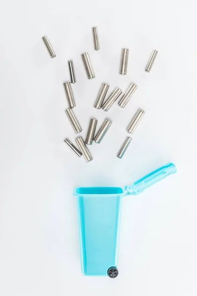 Top view of blue toy trashcan and batteries on grey background — Stock Photo