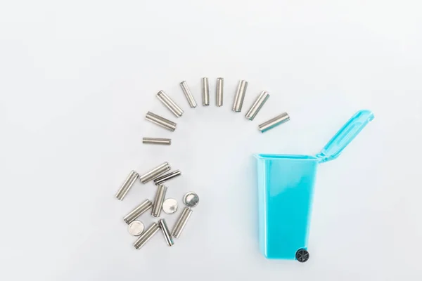 Trashcan de brinquedo azul e baterias em fundo cinza — Fotografia de Stock