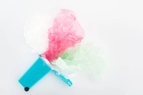 Top view of blue toy trashcan, pink and green plastic bags on grey background — Stock Photo