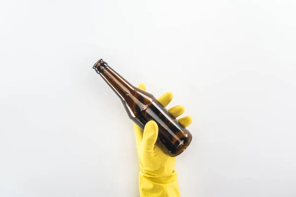 Vista recortada del hombre en guantes de goma amarillos que sostienen la botella de vidrio vacía sobre fondo gris - foto de stock