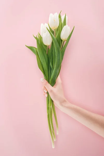 Обрезанный вид женщины, держащей весенний букет с белыми тюльпанами, изолированными на розовый — стоковое фото