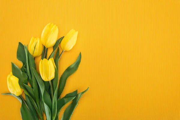 Вид сверху на букет с желтыми тюльпанами на оранжевом фоне — стоковое фото