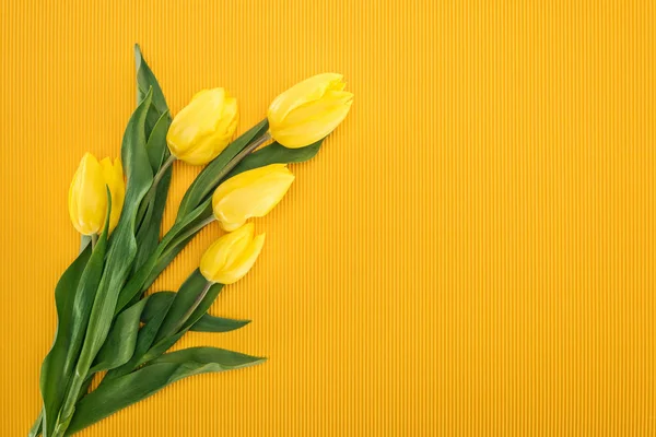 Vista superior del ramo con tulipanes amarillos sobre fondo naranja para el 8 de marzo - foto de stock