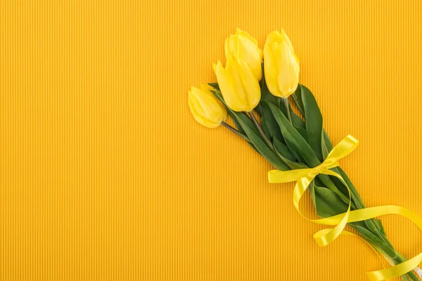 Вид зверху на жовтий букет тюльпан зі стрічкою на помаранчевому фоні для міжнародного жіночого дня — стокове фото