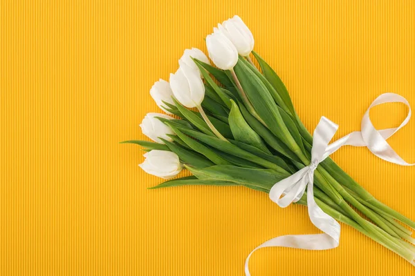 Top view of white tulip bouquet with ribbon on orange background — Stock Photo