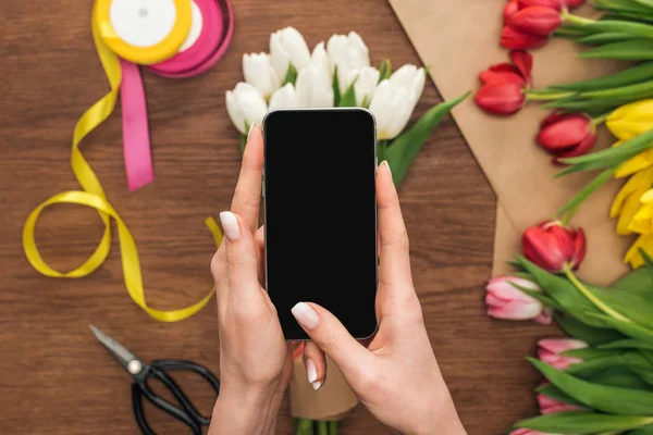 Vista recortada de floristería tomando foto de ramo de tulipán en el teléfono inteligente - foto de stock