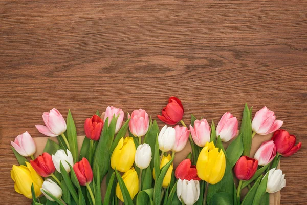 Vue de dessus des tulipes colorées sur fond en bois — Photo de stock