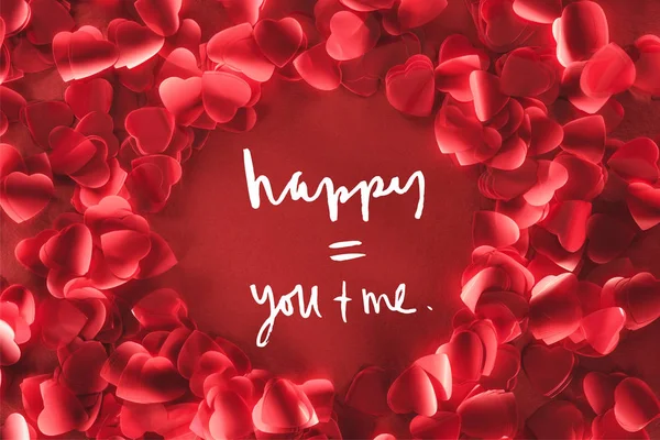 Draufsicht auf schönen runden Rahmen aus dekorativen herzförmigen Blütenblättern auf rotem Hintergrund mit Liebesschrift, Valentinstag-Konzept — Stockfoto