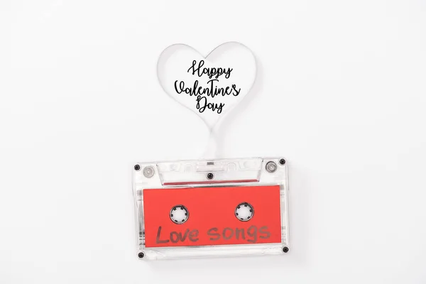 Vista superior de casete de audio con letras de 'canciones de amor' y símbolo del corazón aislado en blanco con letras de 