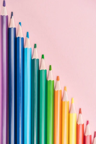 Vista superior de los lápices multicolores del arco iris dispuestos en línea diagonal sobre fondo rosa, concepto lgbt - foto de stock