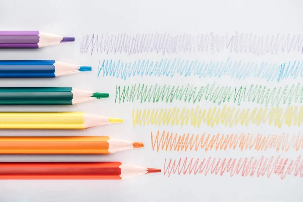 Vista superior de los lápices multicolores arco iris y trazos de colores sobre fondo gris, concepto lgbt - foto de stock