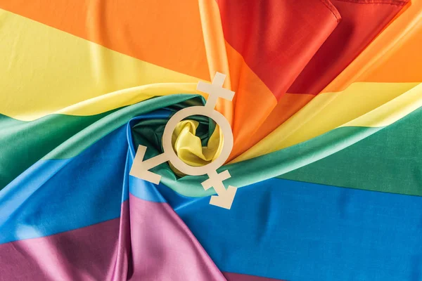 Top view of rainbow flag creased in spiral shape with gender sign, lgbt concept — Stock Photo